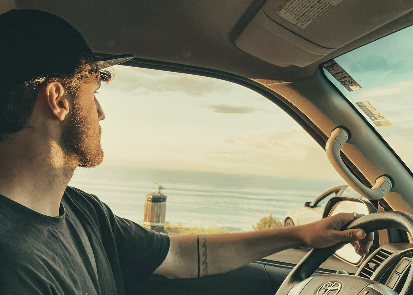 Man driving a vehicle with a scenic view outside the window.