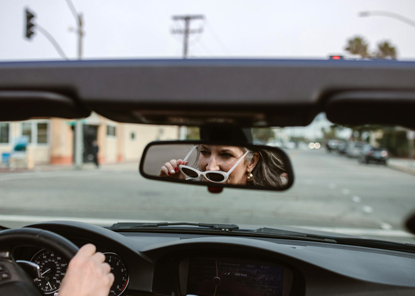 Person driving a car with a reflection of themselves in the rearview mirror.