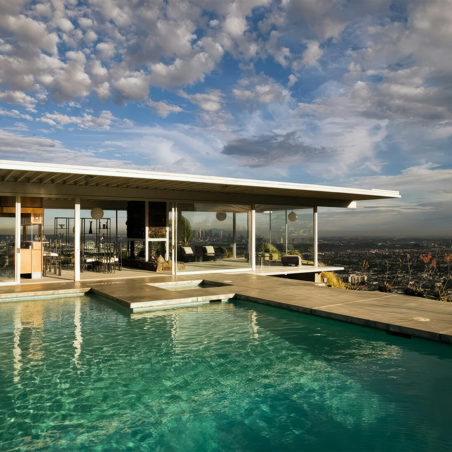 Modern house with a pool and cityscape view under a blue sky with clouds.