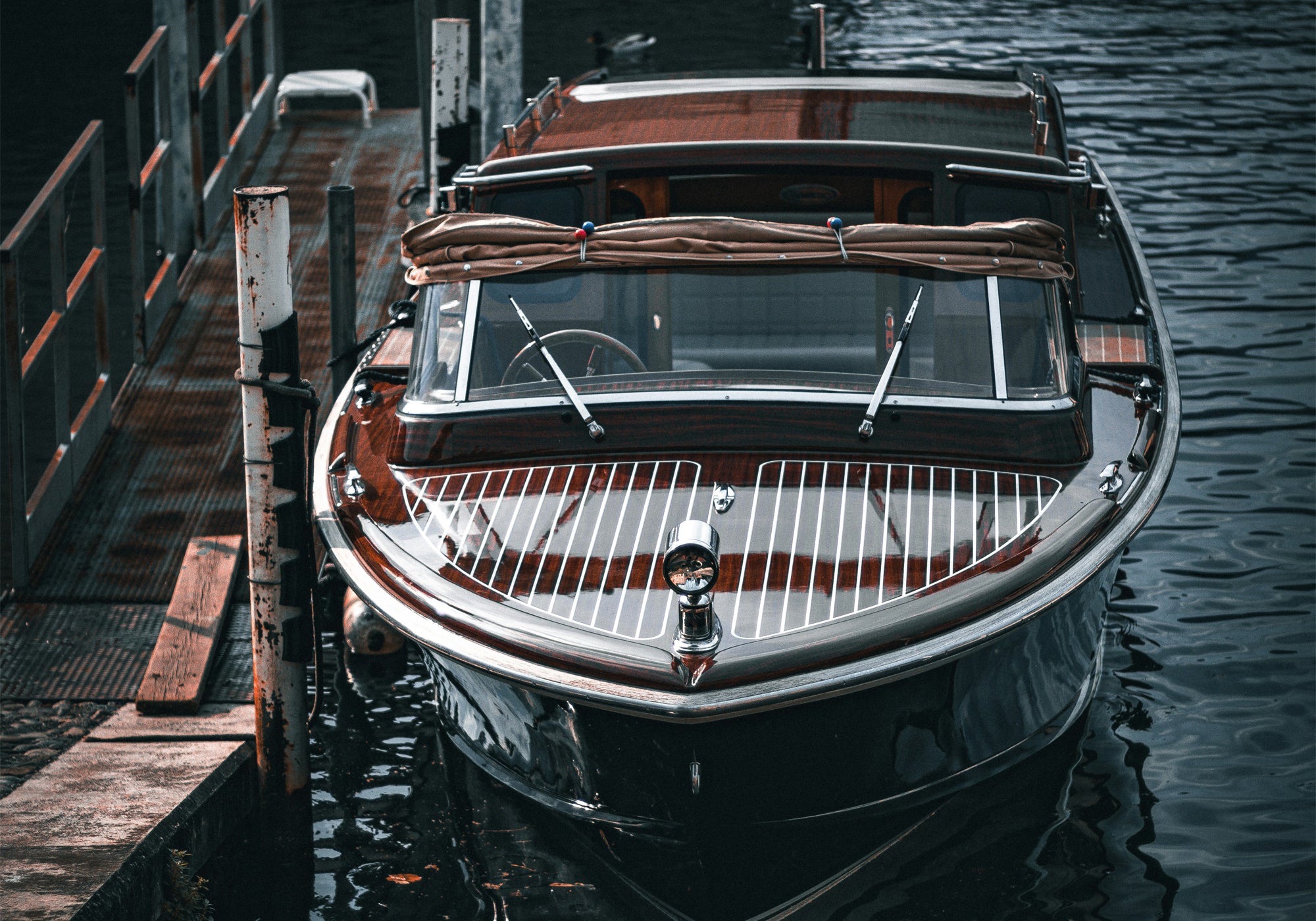 Classic boat docked at a wooden pier on a calm water surface